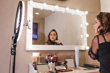 the girl does her own hair at home in front of a large mirror.の写真素材