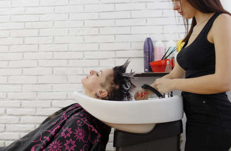 A girl hairdresser washes the hair of a client in a beauty salon.の写真素材
