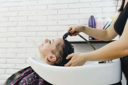 A girl hairdresser washes the hair of a client in a beauty salon.の写真素材