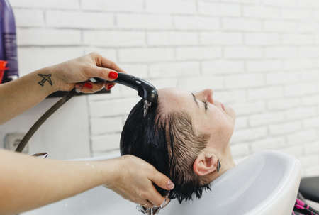 A girl hairdresser washes the hair of a client in a beauty salon.の写真素材