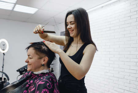 a female hairdresser cuts the ends of womens hair in a beauty salon, close-upの写真素材
