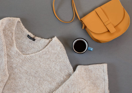 clothes, a cup of coffee, a women's bag laid out on a gray background top view