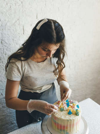 A pastry chef makes a wedding cake with her own hands and puts colorful decorations on the cakes with cream. Preparation for the celebrationの写真素材