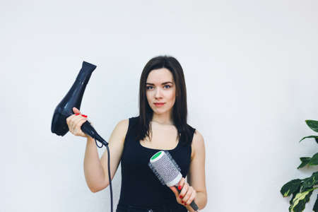 Professional girl hairdresser with hairbrush hair dryer in hand on white backgroundの写真素材