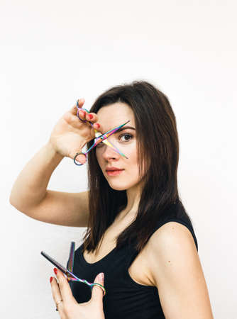 Professional girl hairdresser with scissors in her hands on a white background.の写真素材