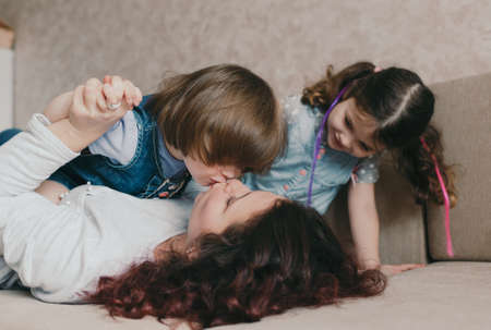 young loving mom and little girl kiss while playing lying on the couch.の写真素材