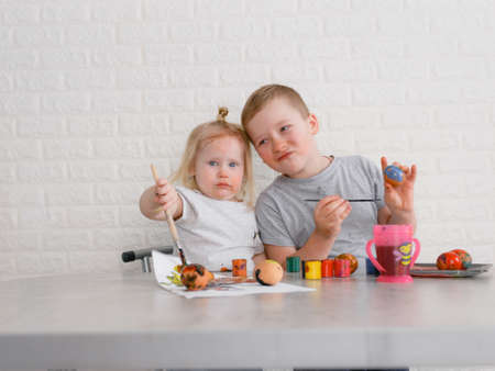 two children paint eggs in the kitchen on the eve of the Easter holidayの写真素材