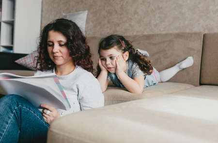 a little girl carefully watches as her mother draws in an album with pencilsの写真素材