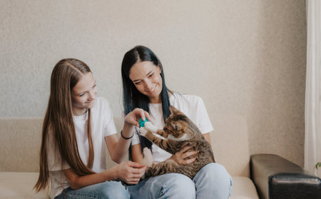 Beautiful mother with her daughter. The family is sitting in the room. A woman plays with a kitten.の写真素材