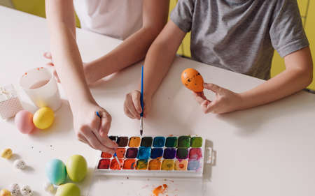 two teenage children paint Easter eggs with colors to prepare for the holiday. top view close-upの写真素材