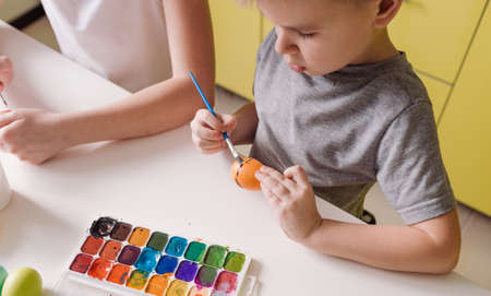 two teenage children paint Easter eggs with colors to prepare for the holiday. top view close-upの写真素材