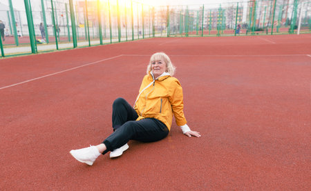 an elderly woman sits and rests after a workout on a red treadmill. healthy lifestyle.
