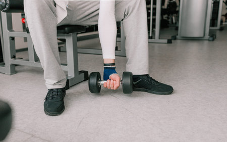 close-up of a man's hand lifting dumbbells. modern gym