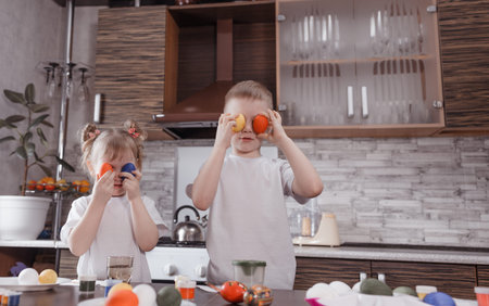 Little kids having fun with painted Easter eggs at home. Brother and sister, holding painted eggs...
