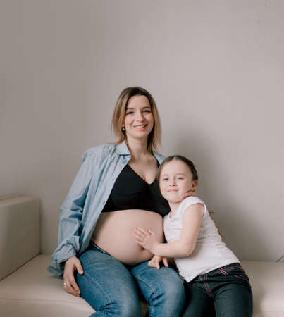 Baby girl and pregnant mother loving little sister next to mother's belly. happy familyの写真素材