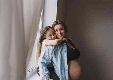 Baby girl and pregnant mother loving little sister next to mother's belly. happy familyの写真素材