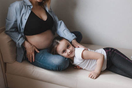 Baby girl and pregnant mother loving little sister next to mother's belly. happy familyの写真素材