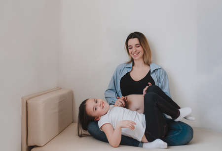 Baby girl and pregnant mother loving little sister next to mother's belly. happy familyの写真素材