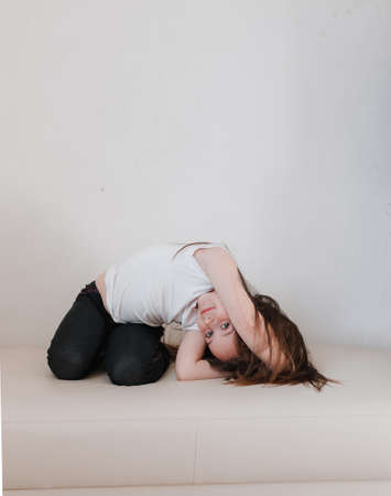 a little girl is doing yoga sitting on the couch. healthy lifestyle in children.の写真素材