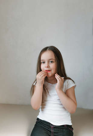 A very funny little girl is trying to make up her lips by doing makeup with her mom's makeup. Happy, smiling and emotional baby faces. Learning to be a woman, trying my mother's lipstickの写真素材