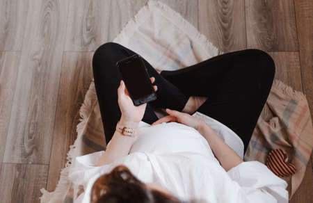 pregnant girl holding a phone in her hands top view. waiting for pregnancyの写真素材