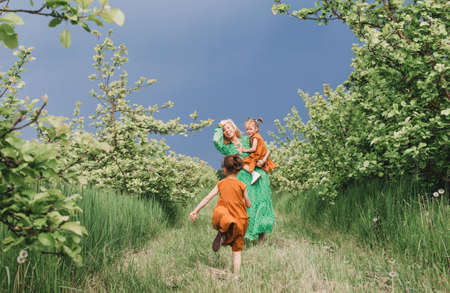 a happy mother in a green dress walks with her two little daughters in the garden before the rain. family happiness and maternal careの写真素材