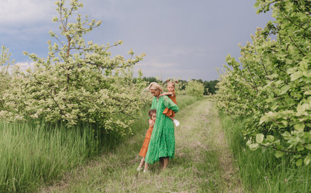 a caring mother plays with her little daughters in a green spring garden. family joysの写真素材