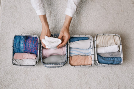 a neat housewife puts things in a laundry container during general cleaning with the help of a...