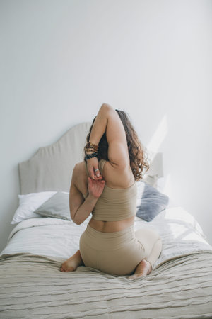 a young girl is doing yoga stretching with her arms crossed behind her back. healthy lifestyle home...