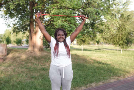 a dark-skinned girl trains in an outdoor park doing exercises with a rope. healthy lifestyleの写真素材
