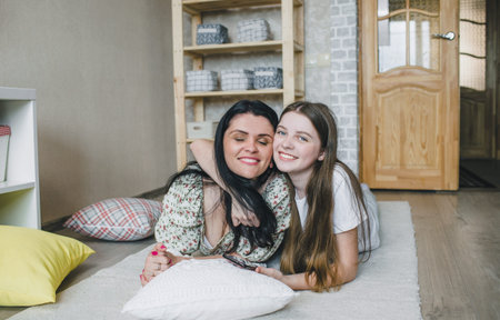 a loving daughter hugs her happy mother lying on the floor in the house. happy family