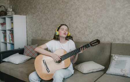 Cute young girl playing guitar sitting on the couch. home schooling