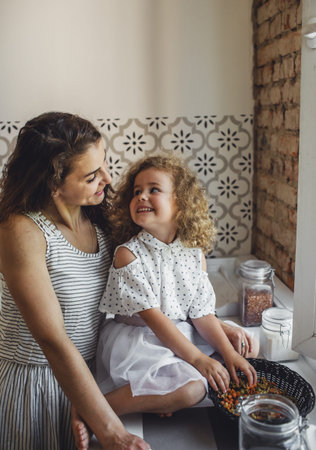 a young mother cooks pasta in the kitchen with her little daughter