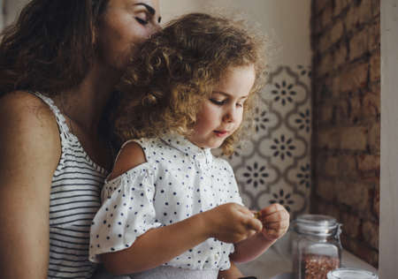 a young mother cooks pasta in the kitchen with her little daughterの写真素材