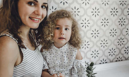 a large portrait of a young mother and her little daughter with curly hairの写真素材