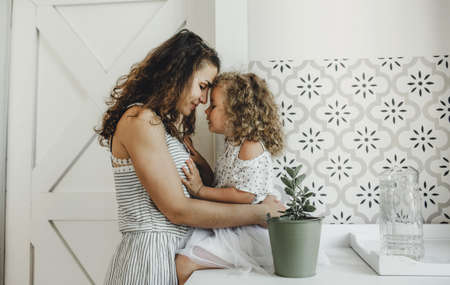 a large portrait of a young mother and her little daughter with curly hairの写真素材