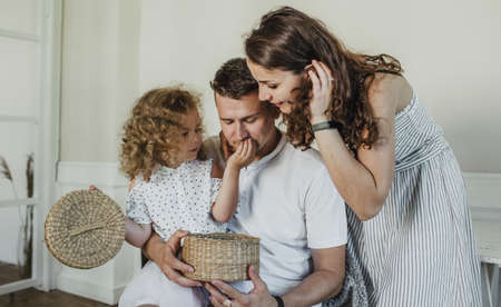 happy family, dad, mom and little daughter play time in the living room opening a box with a surprise. the concept of familyの写真素材