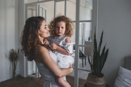 A smiling little girl in her mother's arms. Happy family and the concept of loveの写真素材