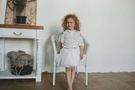 A sad little girl standing on the floor in a large room. sad childの写真素材