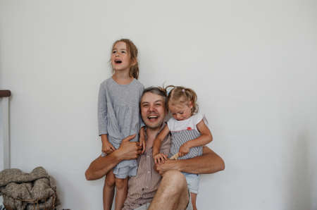 happy dad hugs two little daughters on a light background. caring fatherの写真素材