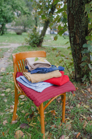 an antique chair with clothes stacked on the street. textiles clothing
