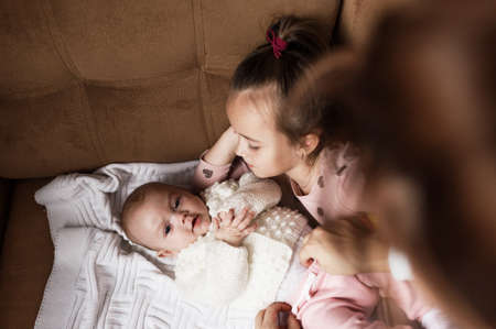 a little girl is playing on the bed with her newborn sister. happy family relationshipsの写真素材