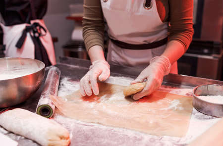 a female chef is working with a dough in the kitchen in a restaurant close-up of her hands.の写真素材