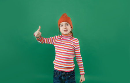 a little girl in a striped sweatshirt smiles and points her finger to the top while standing on a...