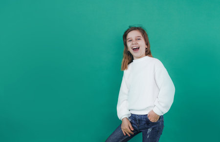 a little girl screams loudly with her mouth wide open on a green isolated background