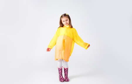 Portrait of a little girl in a yellow raincoat and boots on an isolated white background.の写真素材