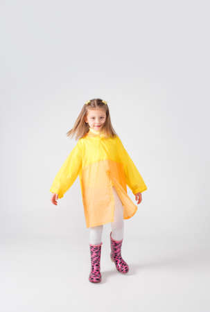 Portrait of a little girl in a yellow raincoat and boots on an isolated white background.の写真素材