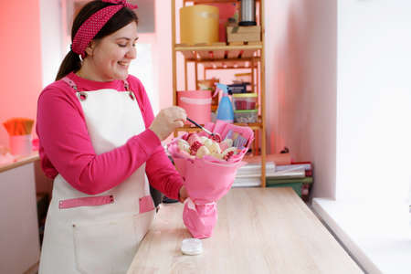 a pastry chef girl collects a beautiful bouquet of chocolate-covered strawberries.の写真素材