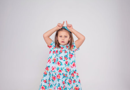 a little beautiful girl in a colored dress poses on a white isolated background.