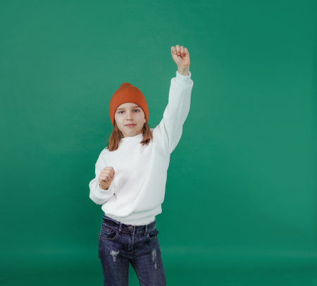The boy is happy. He is wearing a white sweater and jeans. He raised his right hand up. children's joyの写真素材